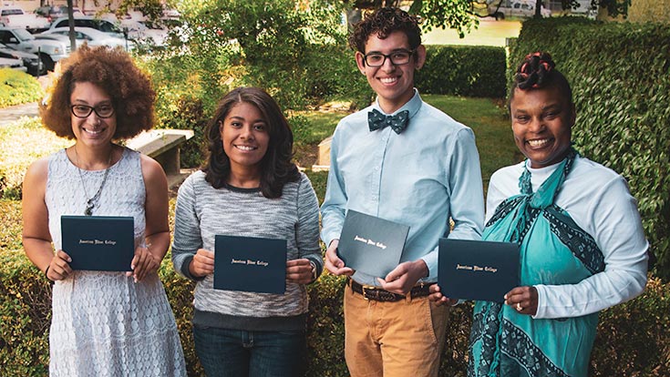 Four students holding their scholarship awards and smiling